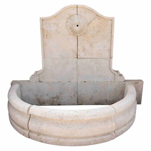 Fuente de pared de mármol tallado con una pileta semicircular y una roseta clásica.