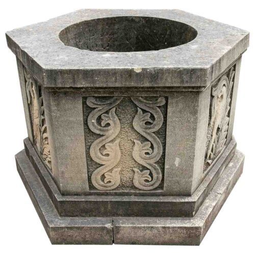Cabezal de pozo octogonal de piedra tallada con relieves ornamentales